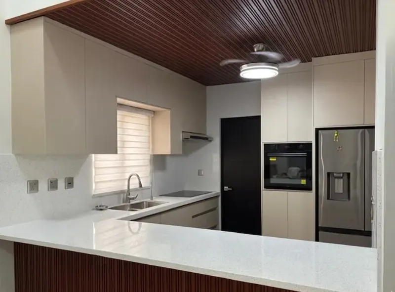 Cocina integral de melamina con cubierta de cuarzo blanco, barra y lambrín de madera en Hermosillo, Sonora